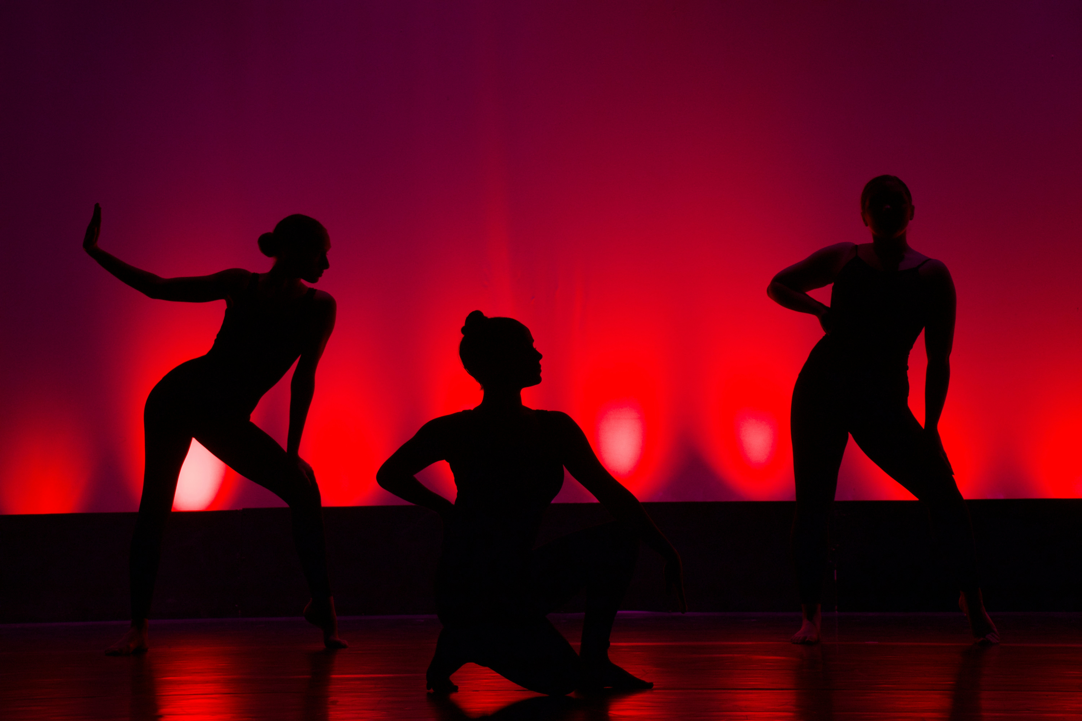 Black and white photo of teens rehearsing a dance routine on a stage.