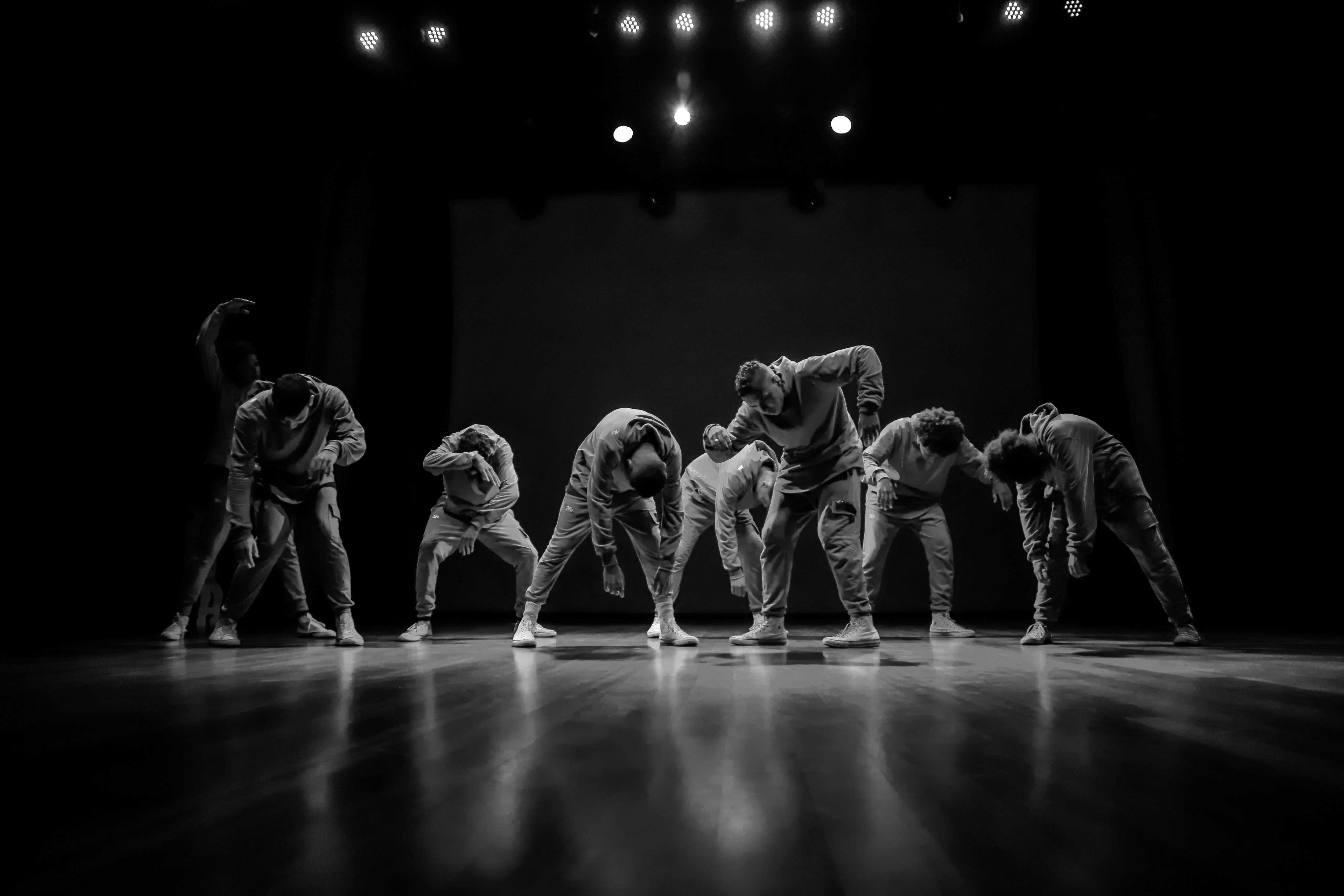 Black and white photo of a group of men performing modern dance on a stage.